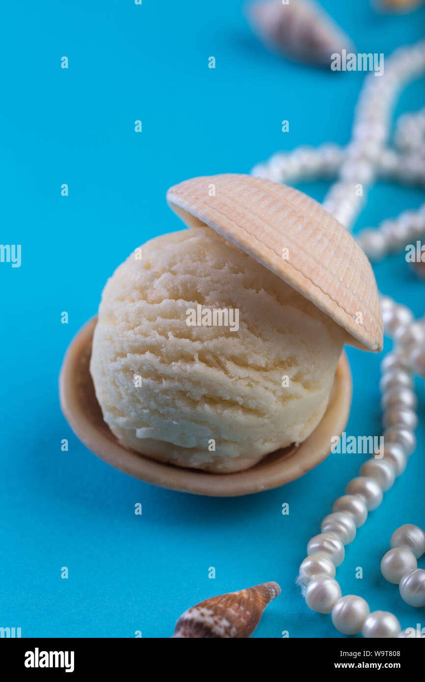 vanilla ice-cream like pearl in sea shell on blue background deep sea pearl necklace space for text Stock Photo