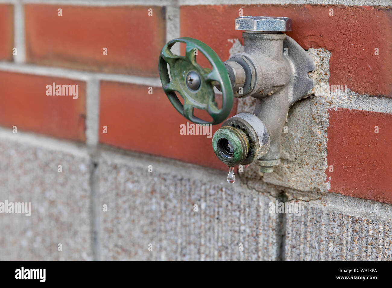 Old corroded outdoor water spigot, faucet, or tap leaking, dripping water and needing repair Stock Photo