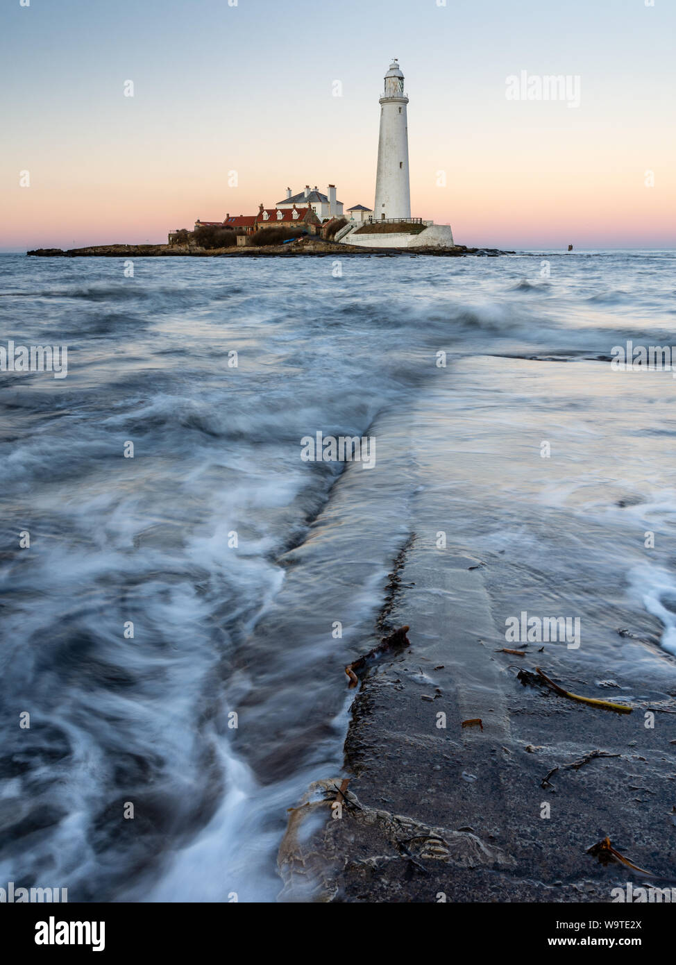 Waves flow across the St Mary's Island Causeway at dusk, with St Mary's Lighthouse behind, on the Whitley Bay coast of Tyneside. Stock Photo