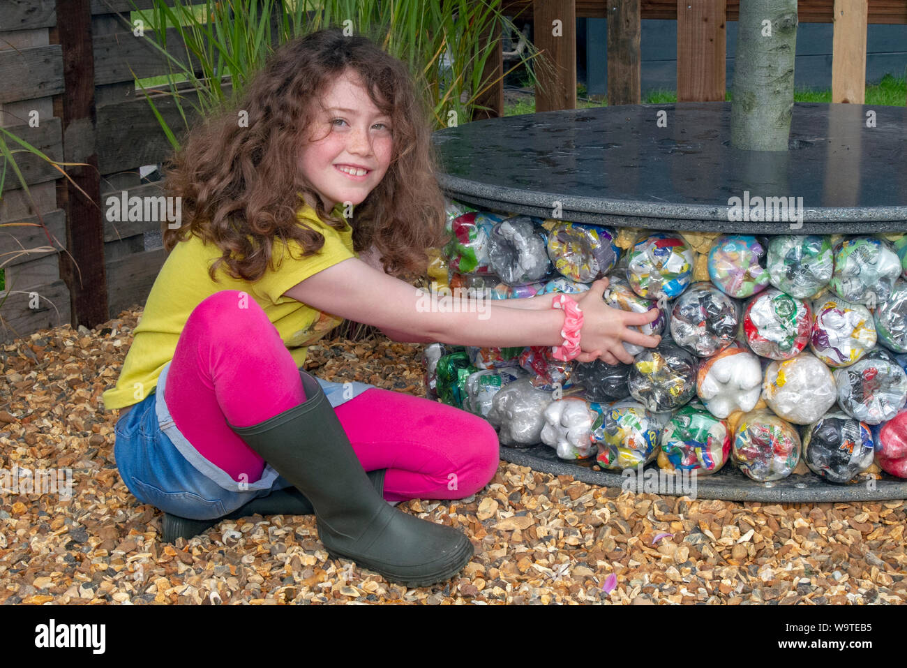 Southport, Merseyside. UK Weather.  Aug, 2019. 9 year old Silvie McGuiness & Upcycled reused plastic bottle tree seat in Victoria Park. Katie from Wigan council in the Waste Not Want upcycling garden Not garden. The first Southport Flower Show was held in the 1920s, organised by local businessmen who wanted to celebrate the region’s horticulture. It has grown into Britain’s largest independent flower show and one of the highlights of the north-west’s summer calendar. Stock Photo