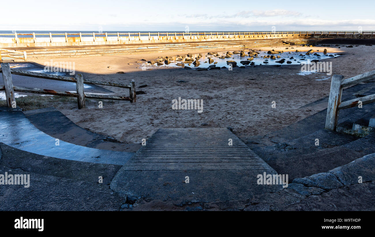 Water pools amongst sand and rocks filling the disused Tynemouth Outdoor Pool lido on the North Sea coast of Tyneside. Stock Photo