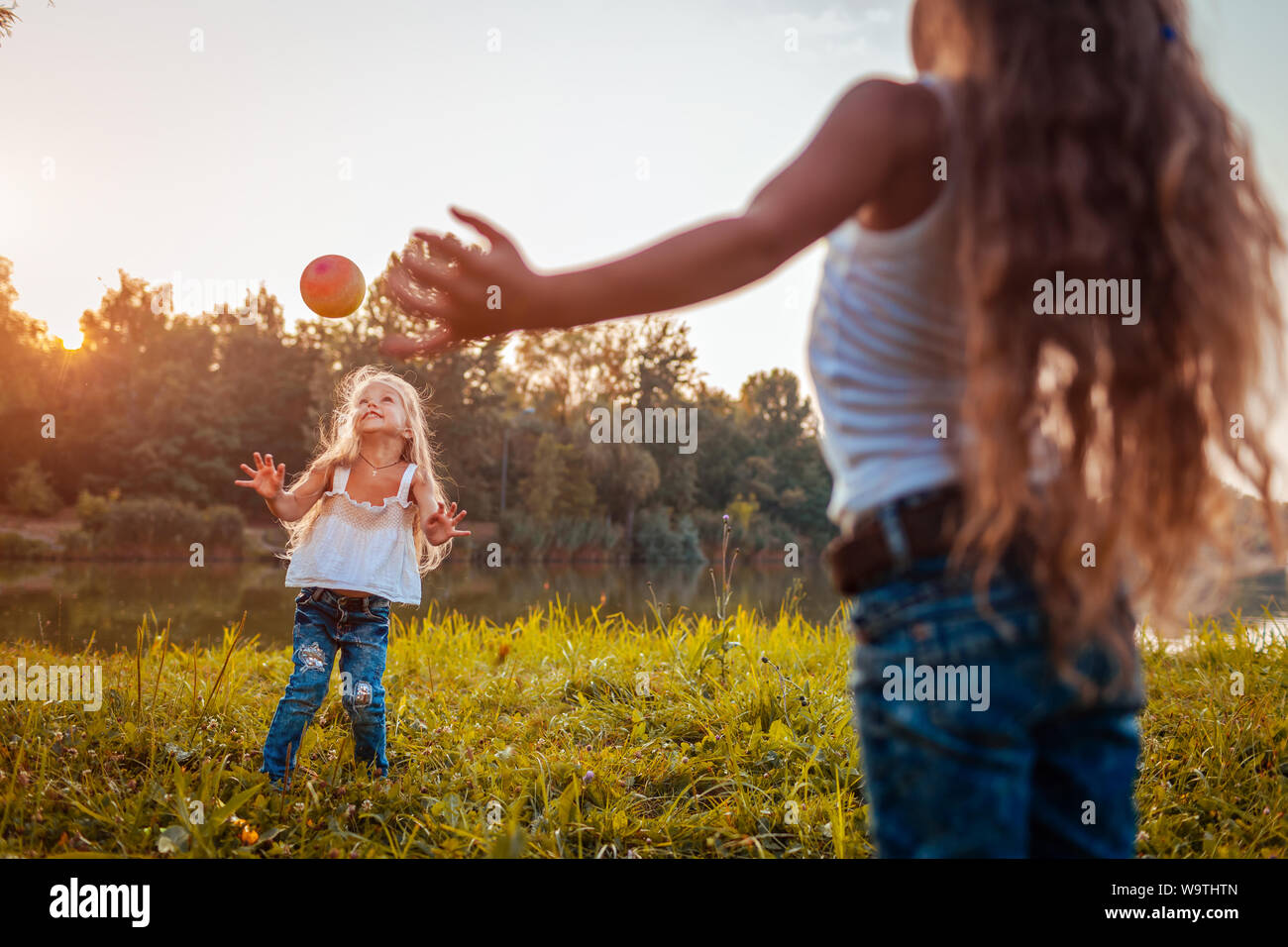 Little girls playing with ball in summer park. Kids having fun outdoors ...