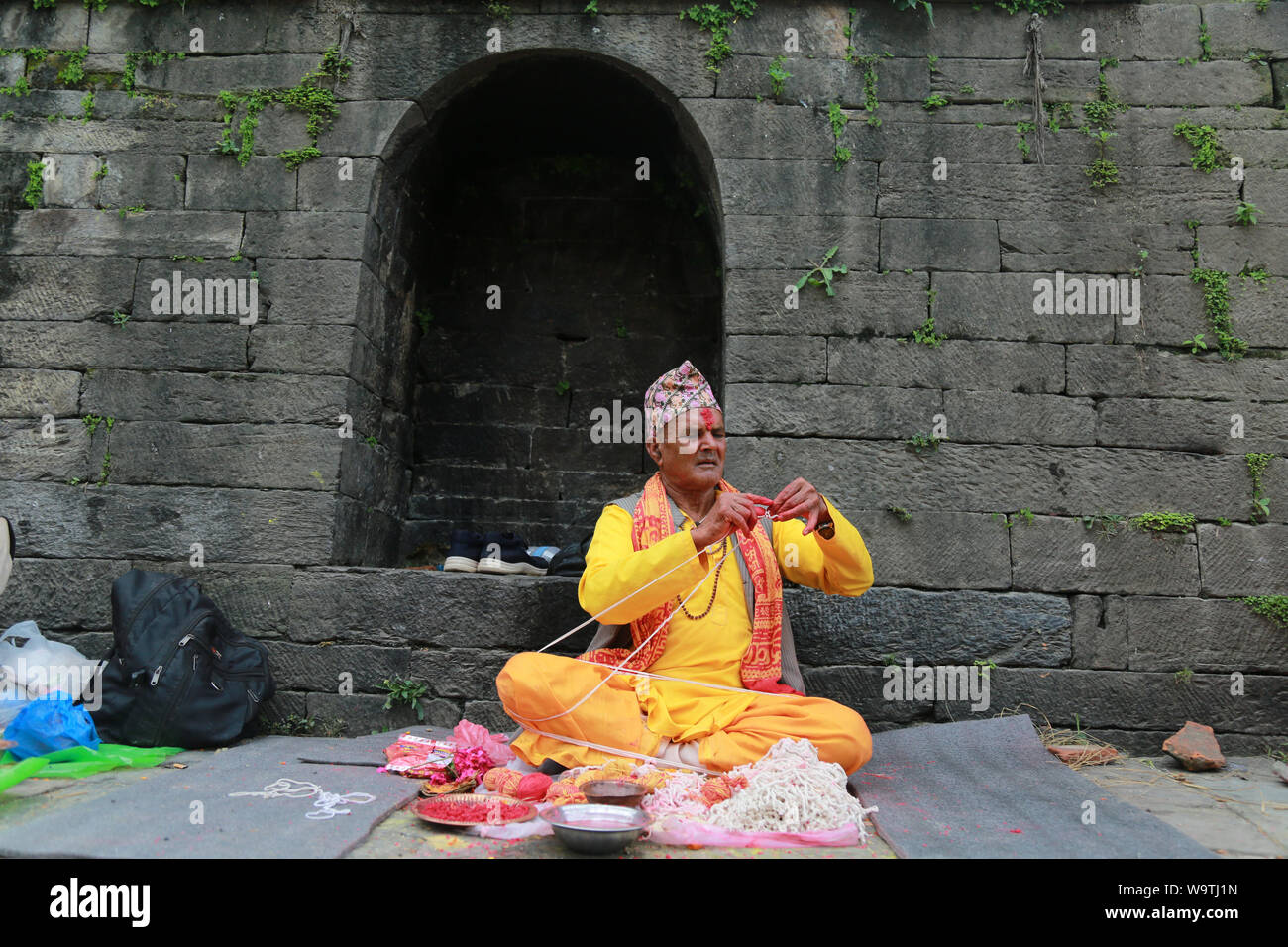 Kathmandu, Nepal. 15 August, 2019. A Nepali Hindu priest holds janai or sacred thread as he waits for devotees. Sarita Khadka/Almy Live News Stock Photo