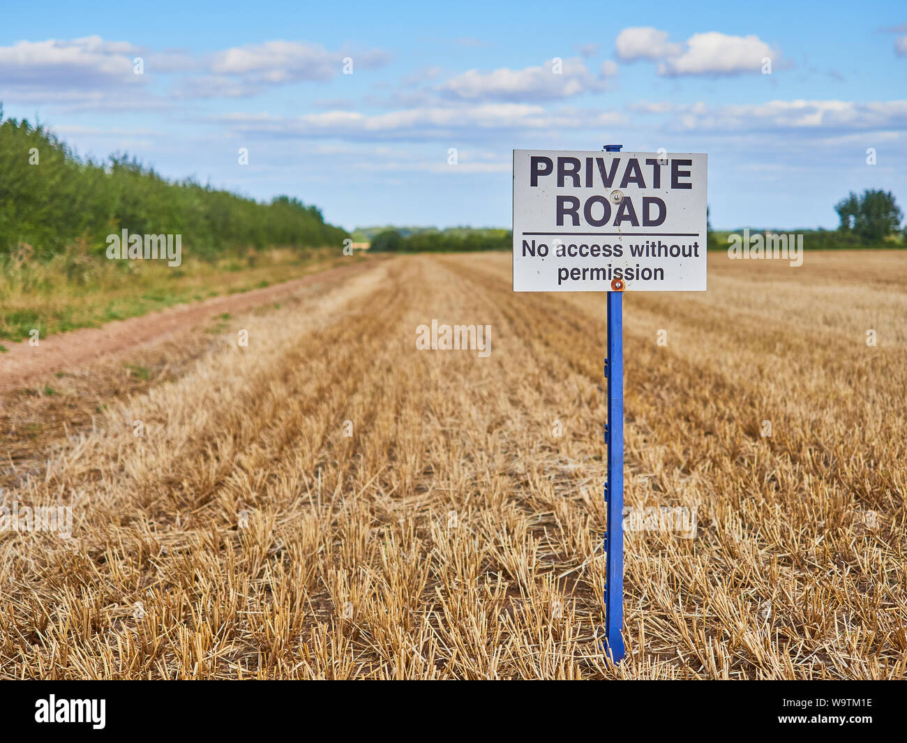 A Private Road. No Access Without Permission sign on a post at the side of a farm track next to an arable stubble field Stock Photo