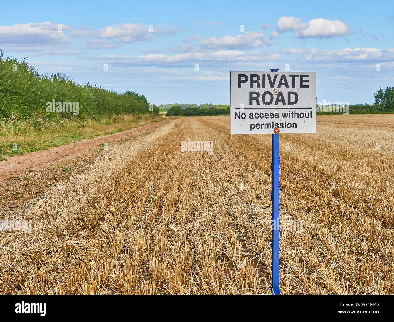 A Private Road. No Access Without Permission sign on a post at the side of a farm track next to an arable stubble field Stock Photo