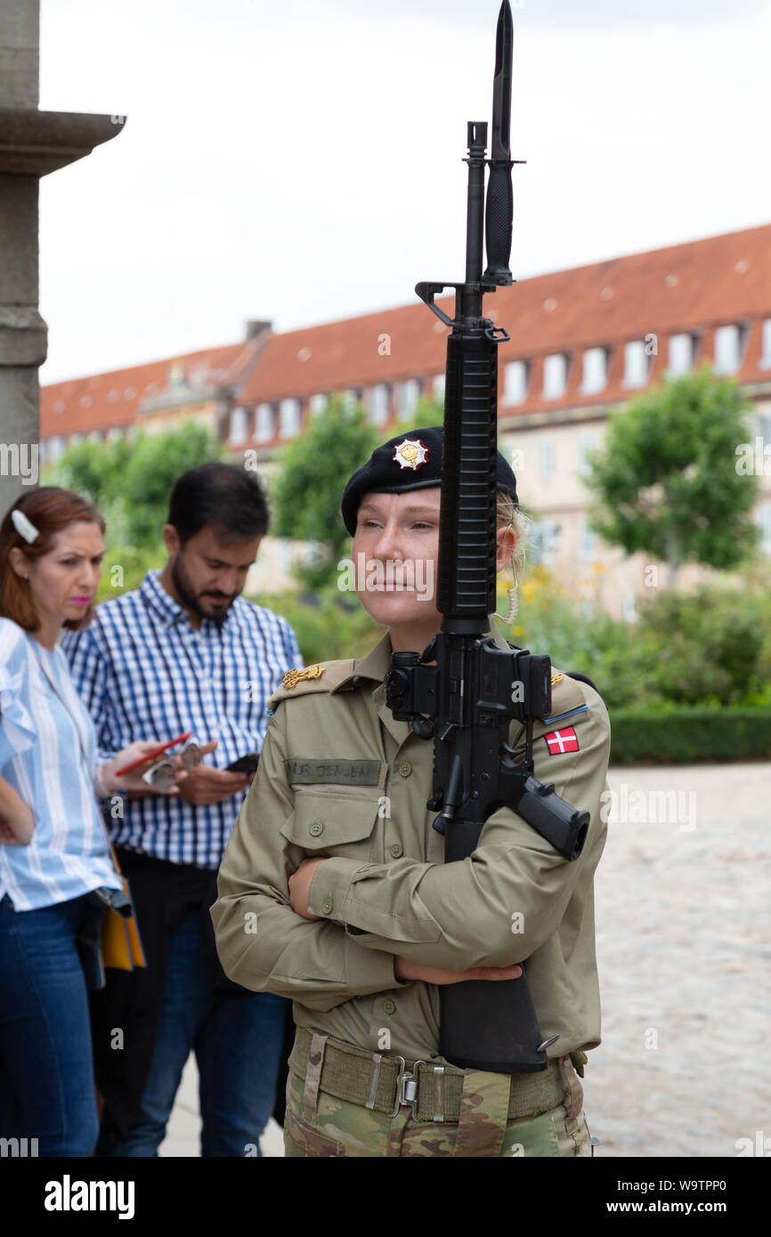 Tourists looking at a woman soldier armed with a rifle; A female soldier on guard duty; Rosenborg Castle, Copenhagen Denmark Europe Stock Photo