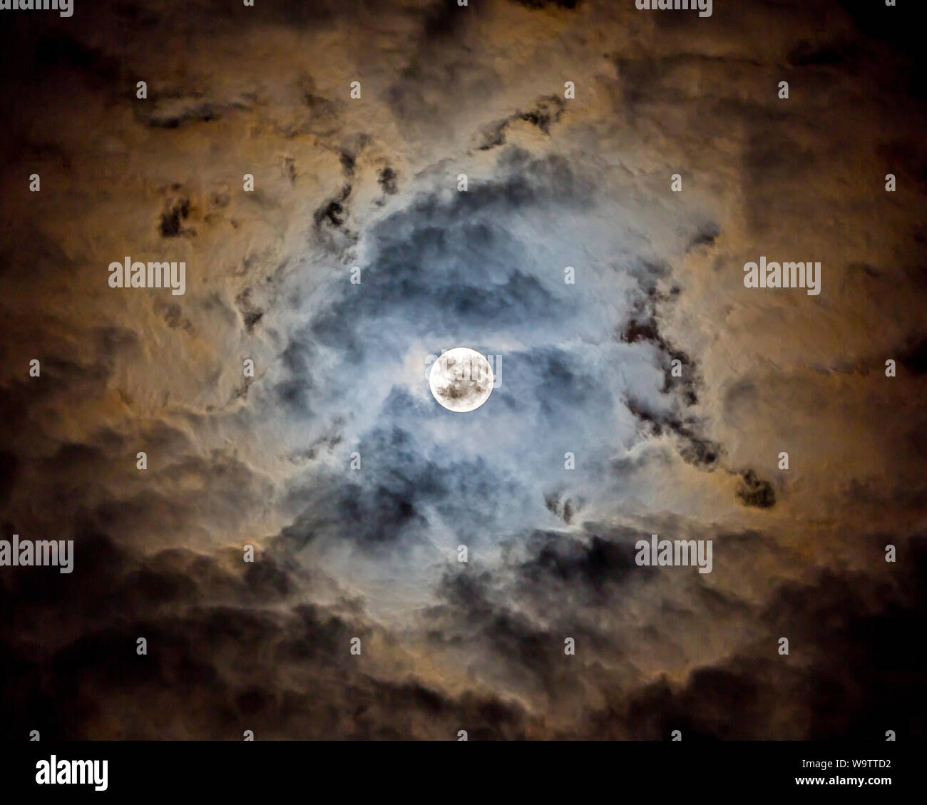 The glow of a full moon dramatically lights clouds in a night sky Stock ...