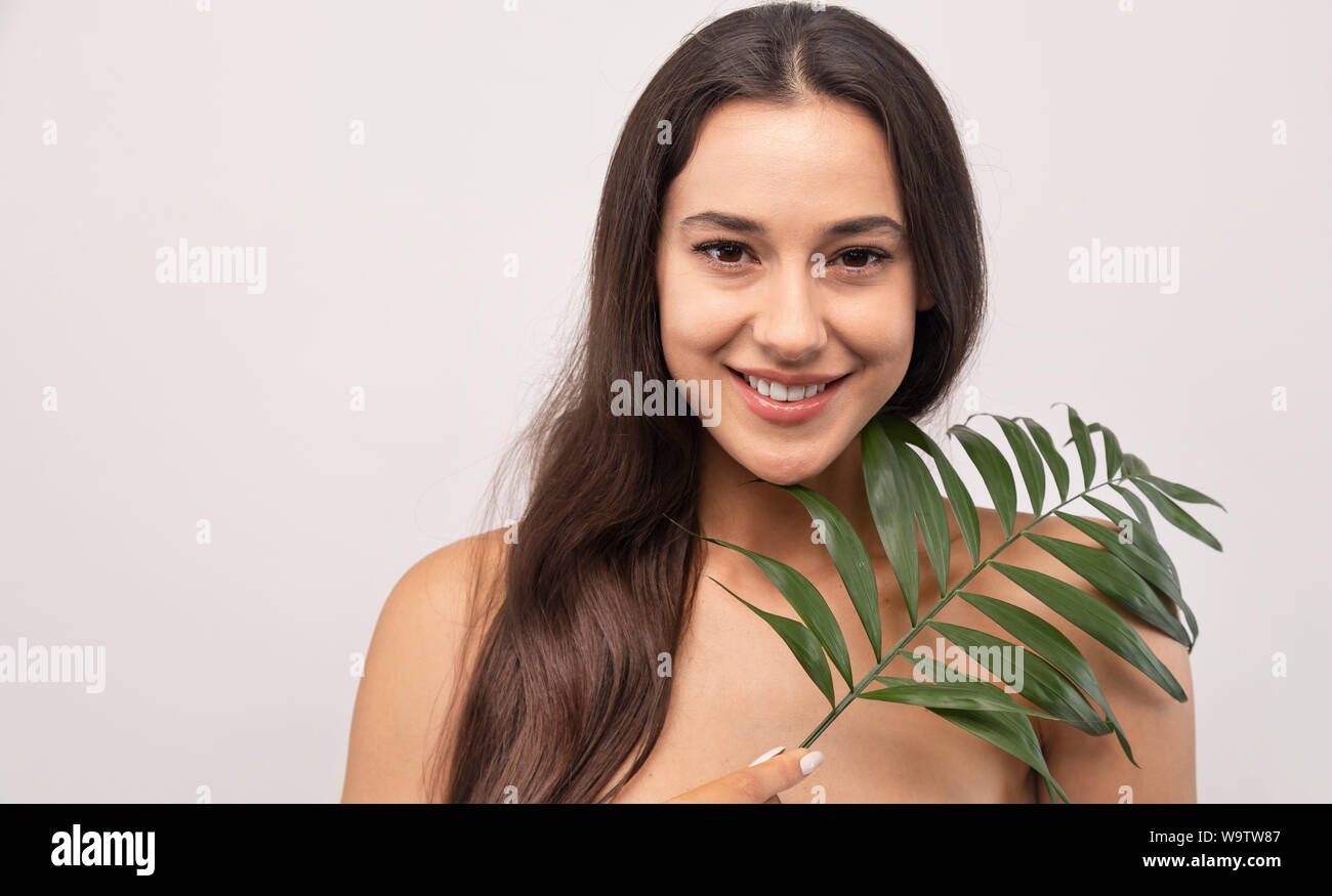 Portrait of beautiful female model with a green sprig looking at camera isolated white background copyspace Stock Photo