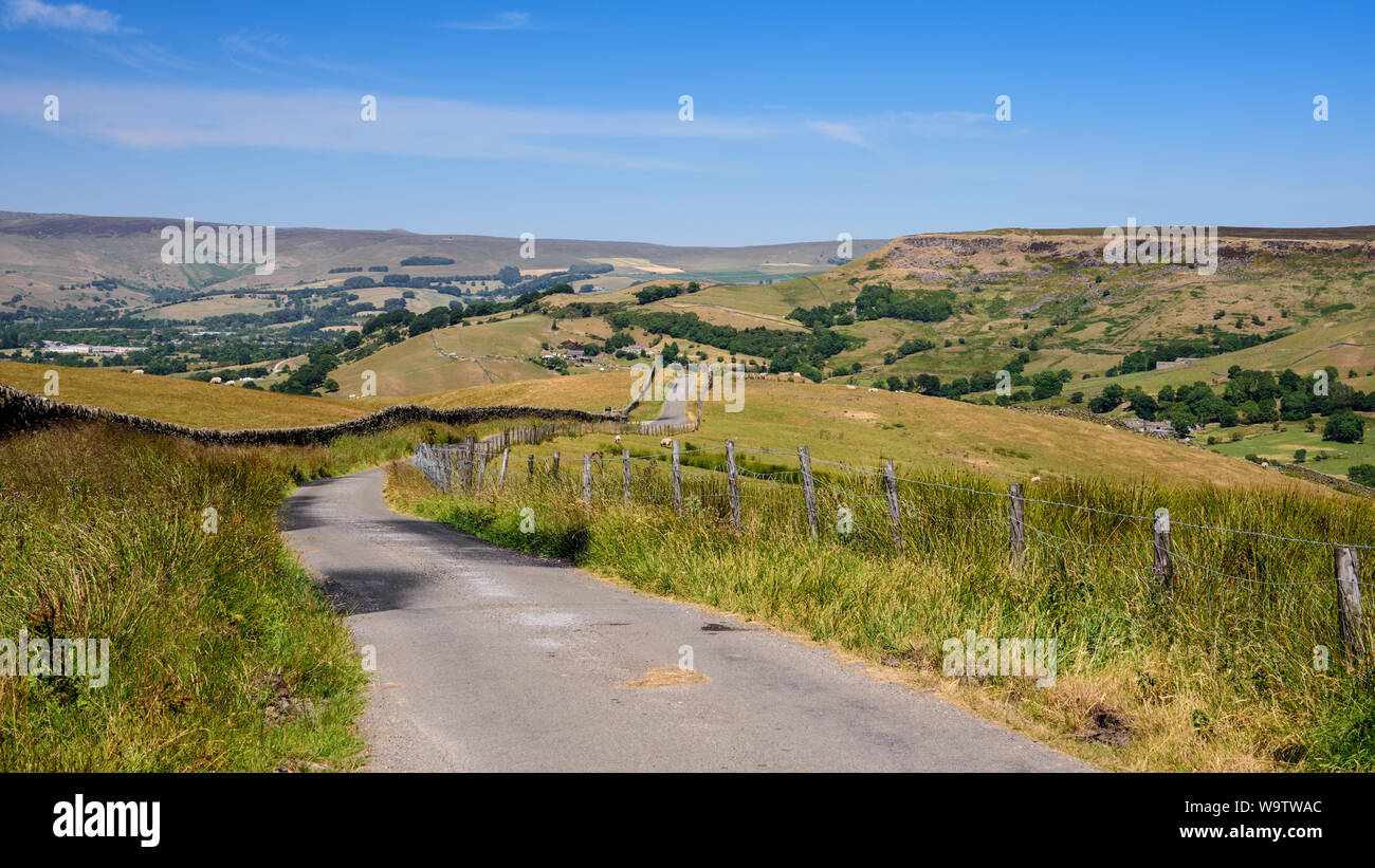 Characteristic flat-topped gritstone moors with craggy escarpments rise above valleys of pasture farms and the town of Chapel-en-le-Frith in the High Stock Photo