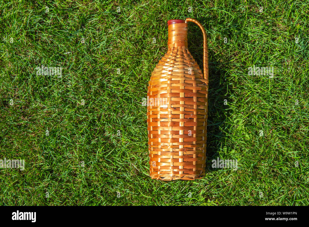 Rattan wine bottle laying on green grass lawn , pic nic concept Stock Photo