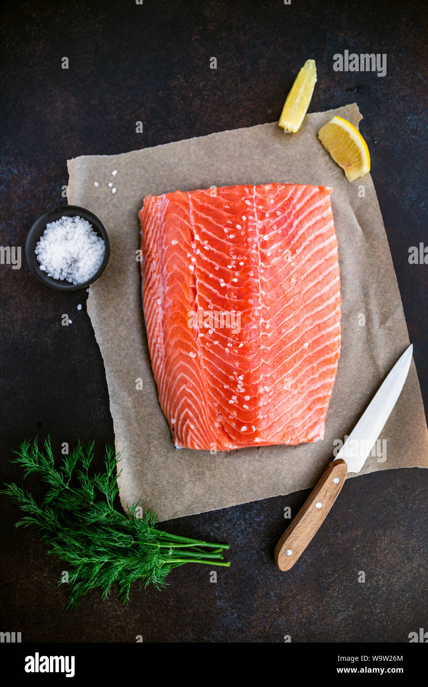Top view of fresh raw salmon fillet with dill, sea salt and lemon on a table for cooking. Recipe for ketogenic or paleo diet. Stock Photo