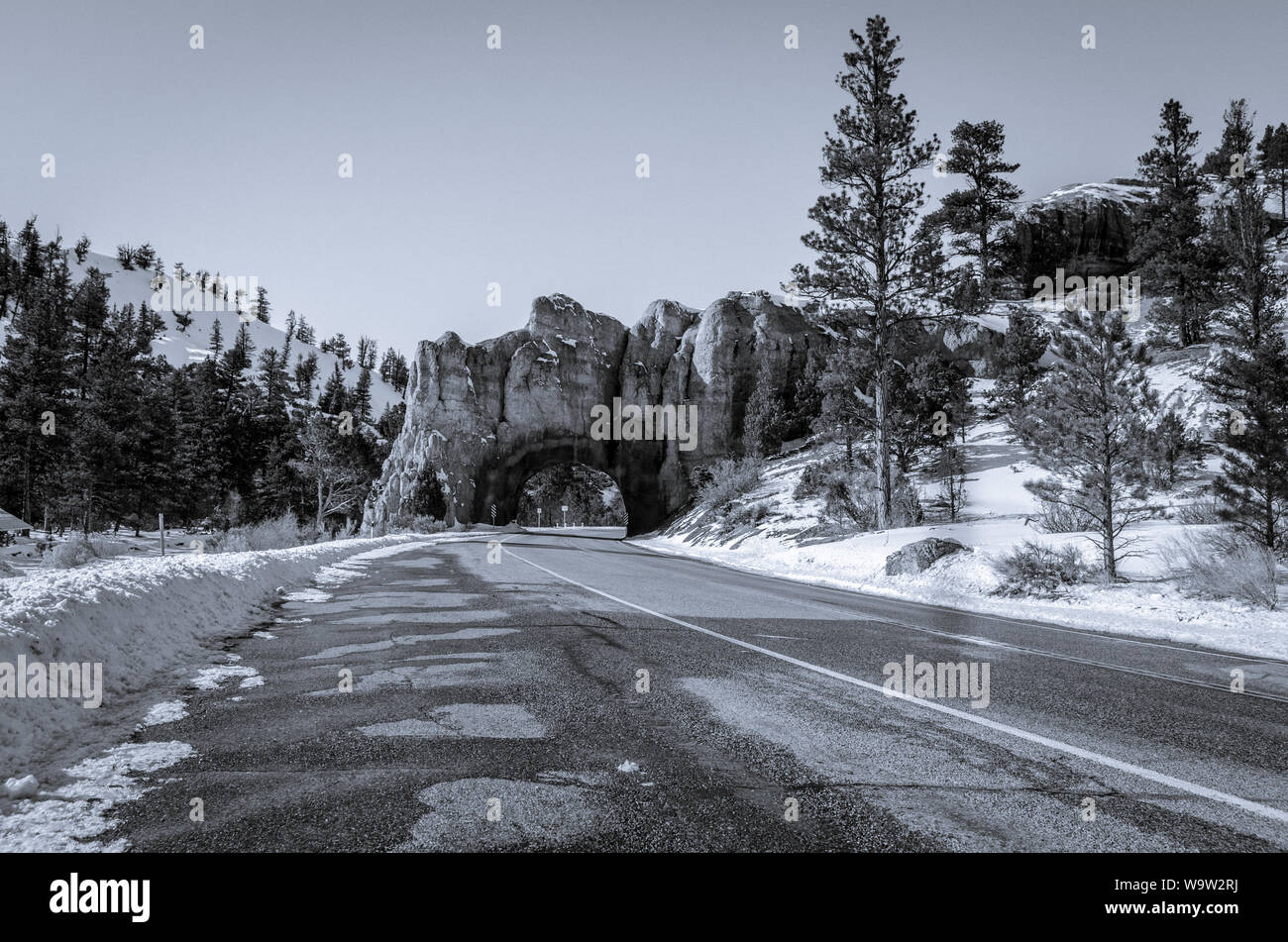 Lonely Utah road covered in snow with tunnel in the background. Stock Photo