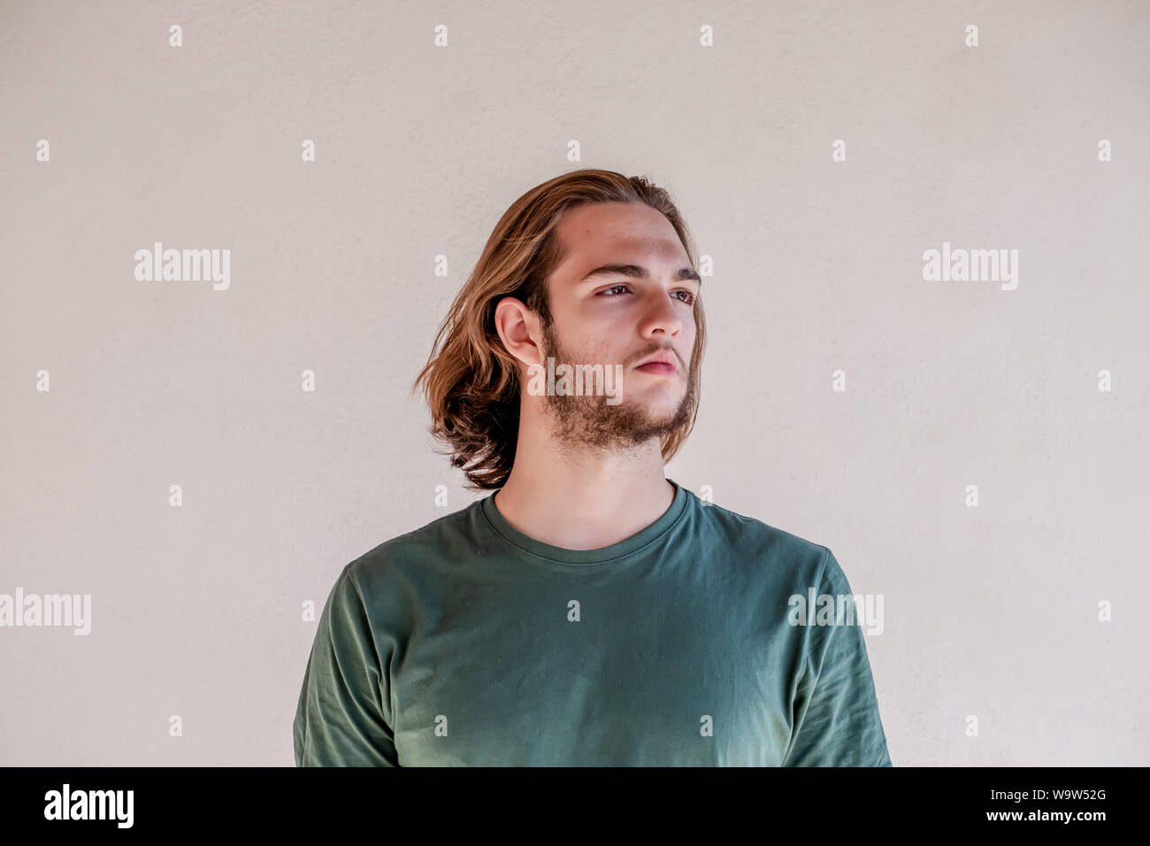 Long haired blonde man looking right, handsome bearded young guy turn the right Stock Photo
