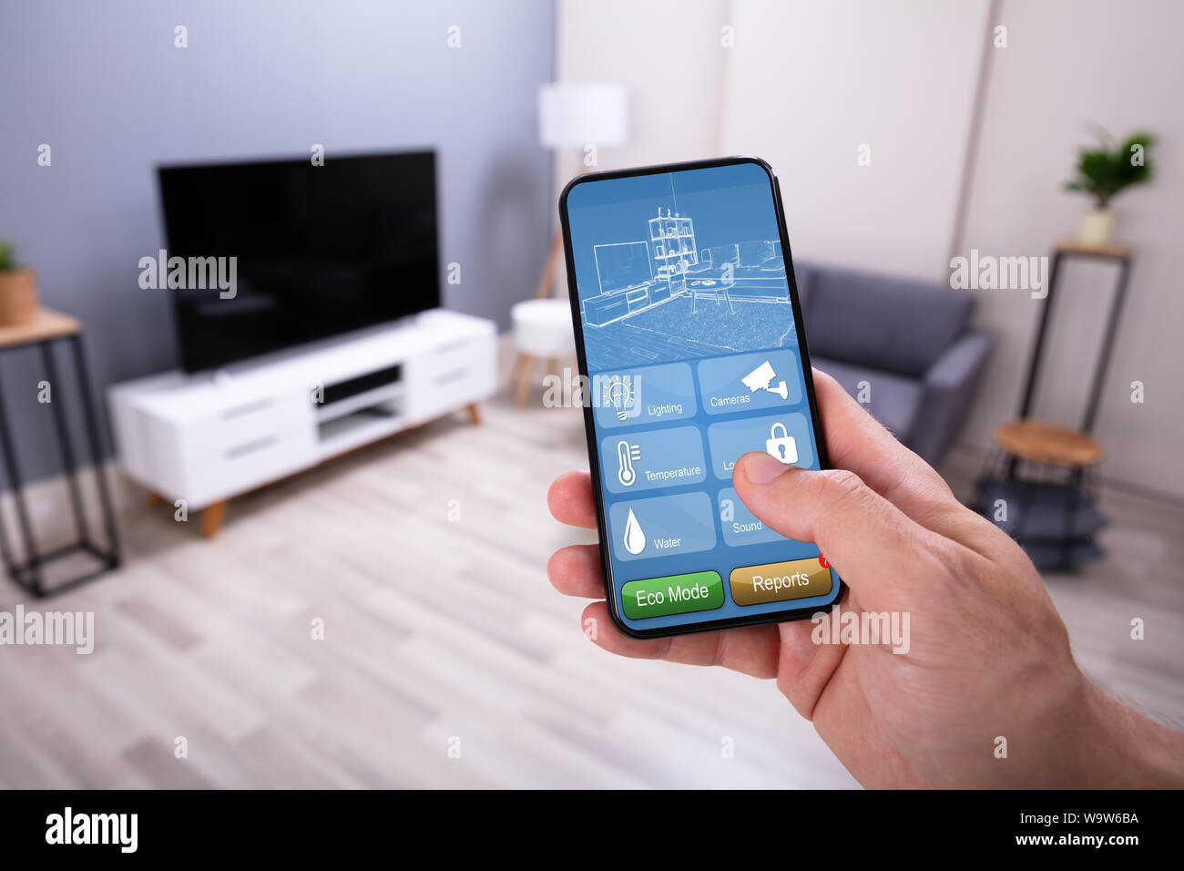 Man Using Smart Home Application On Mobile Phone Stock Photo