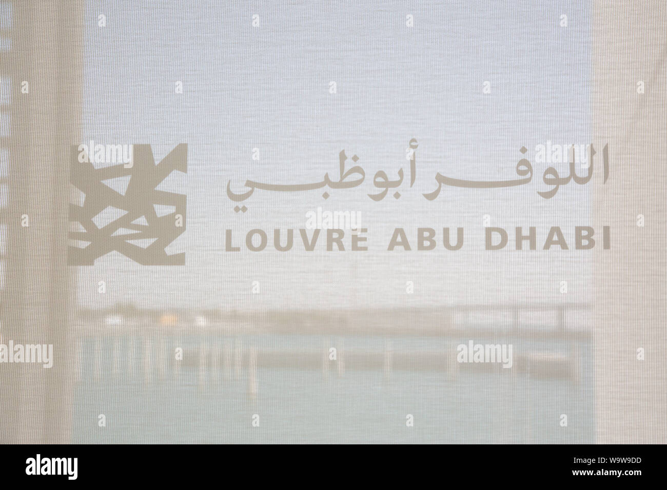Louvre Abu Dhabi logo on the window of the museum. --- The Louvre Abu Dhabi is an art and civilization museum, located in Abu Dhabi, UAE Stock Photo
