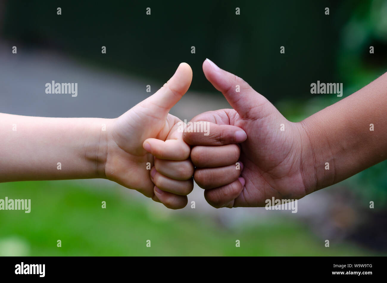 White Boy and black girl show thumbs up or 'like' gesture. Conceptual photo expresses friendship, peace, support, equality and diversity. Stock Photo