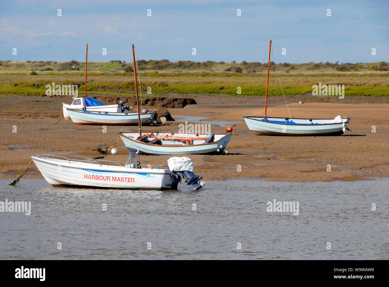 The Harbour Master's boat and other boats stranded at Brancaster Staithe, on the north Norfolk coast, at low tide Stock Photo
