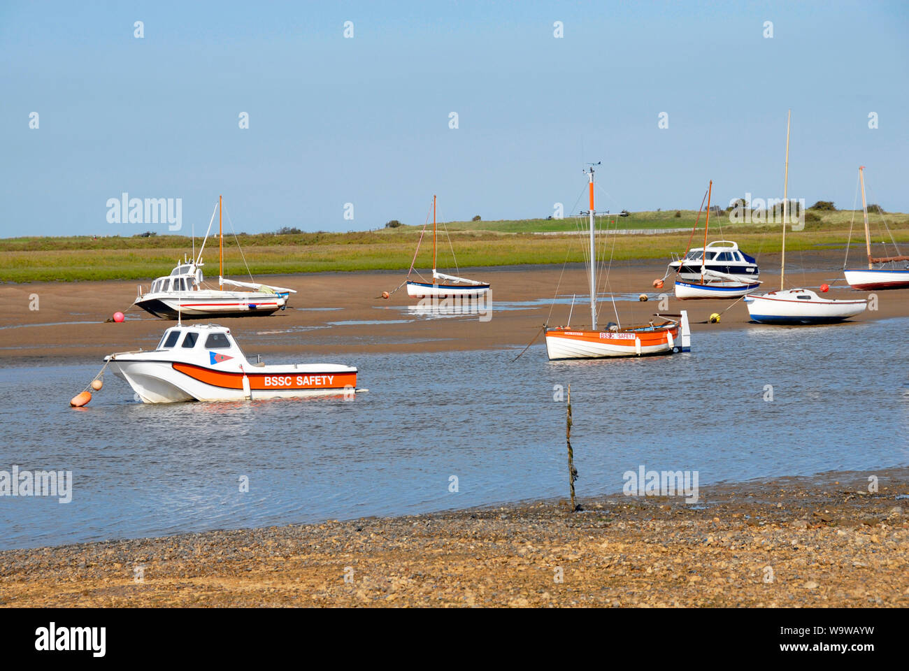 Small boats stranded in shallow stream at Brancaster Staithe, on the north Norfolk coast, at low tide Stock Photo