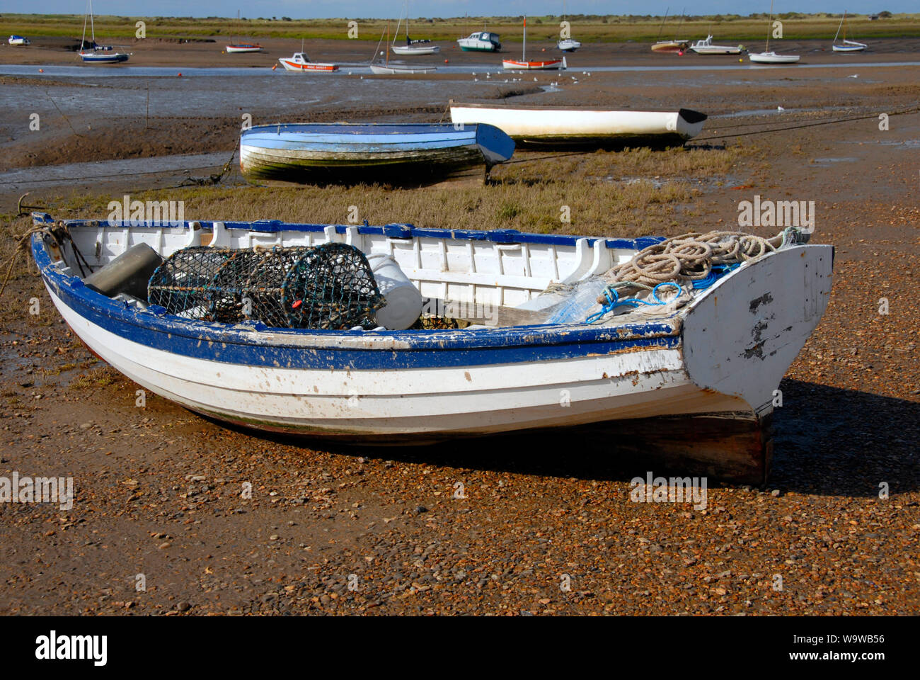 Small boats stranded on the beach at Brancaster Staithe, on the north Norfolk coast, at low tide Stock Photo