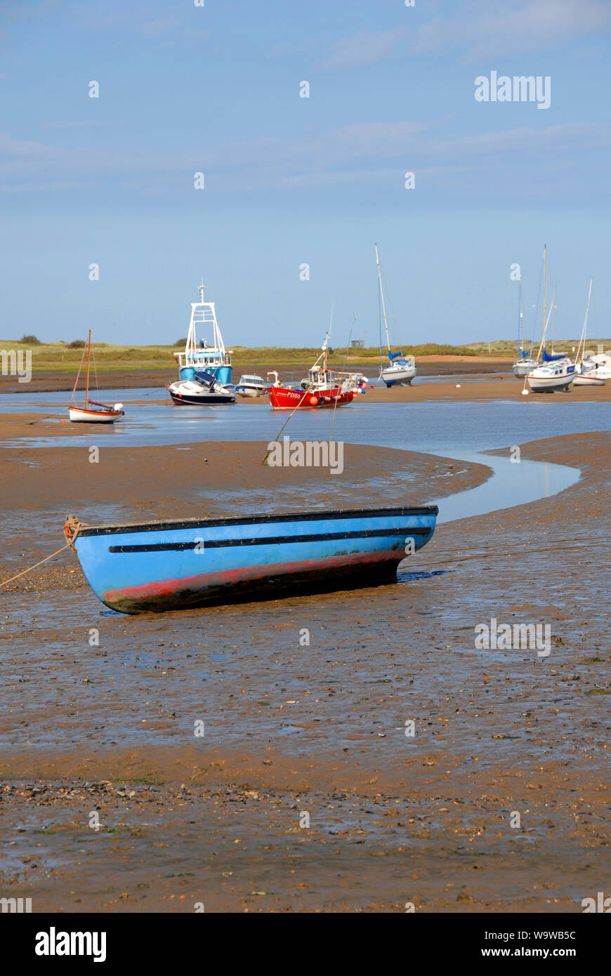 Boats stranded on the mud at Brancaster Staithe, on the north Norfolk coast, at low tide Stock Photo