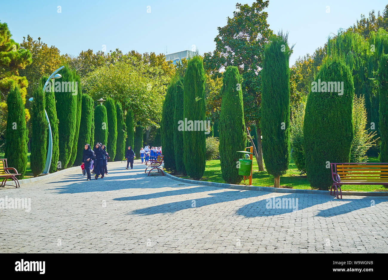 TEHRAN, IRAN - OCTOBER 25, 2017: The group of little Iranian schoolgirls, dressed in uniforms and hijabs, runs and plays during excursion to Laleh Par Stock Photo