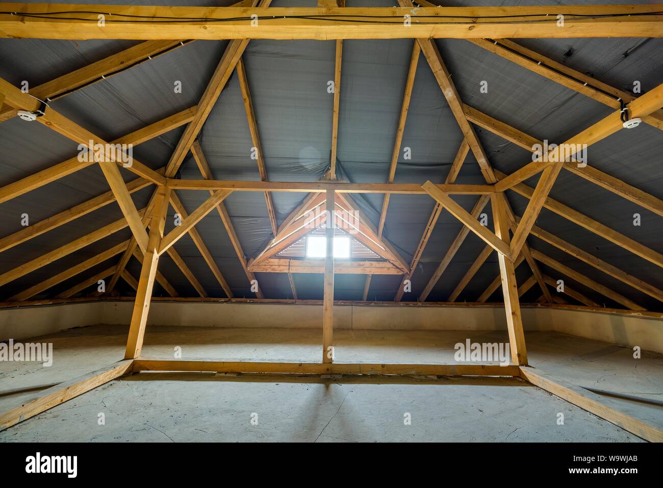 Attic of a building with wooden beams of a roof structure and a small ...
