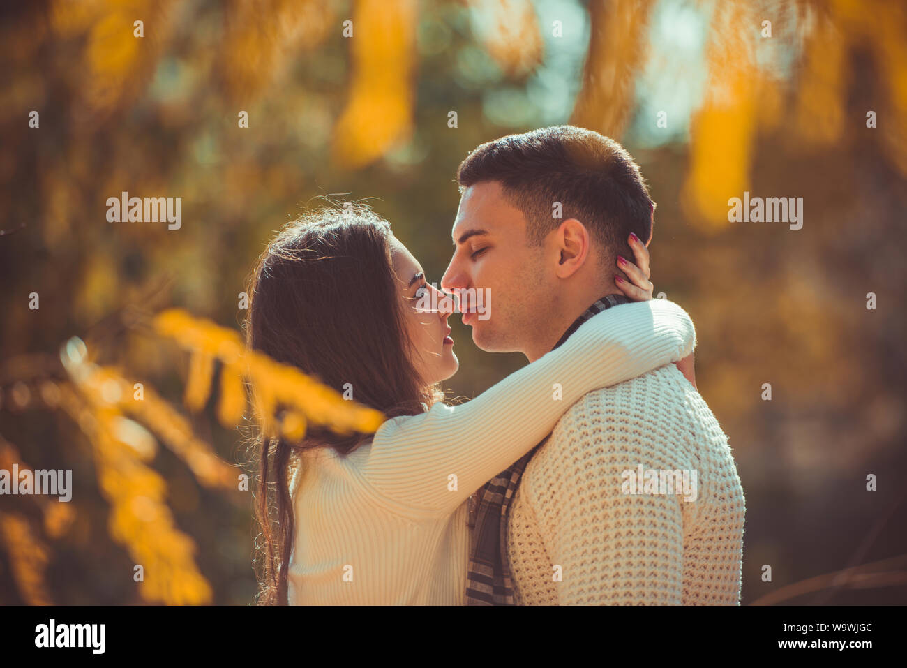Pretty couple is enjoying the daily sunlight and kissing in the park ...