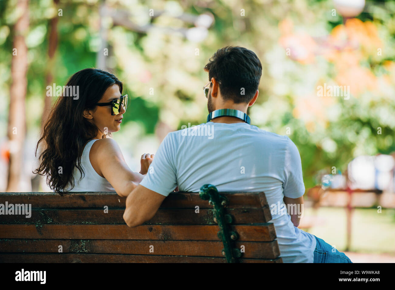 Back view of beautiful love couple sitting outdoors on a bench looking each  other Stock Photo - Alamy