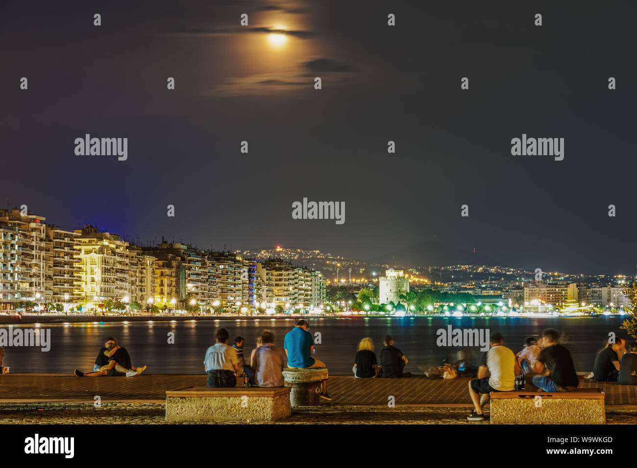 August full moon over Thessaloniki, Greece waterfront. 2019 summer moon rising over White Tower landmark, seen from the city port. Stock Photo