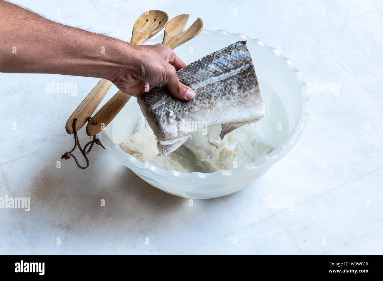 Salted and dried cod fish (Gadus morhua) in plastic bowl filled with water to desalt and be