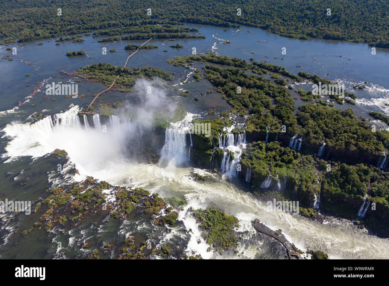Aerial view of forest and waterfalls in Iguazu river in sunny summer day. Foz de iguaçu divides the border between Brazil and Argentina and is One of Stock Photo