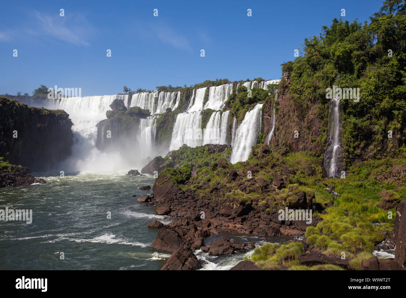 Beautiful view of waterfalls on Iguazu river in sunny summer day. Foz de iguaçu divides the border between Brazil and Argentina and is One of the Seve Stock Photo