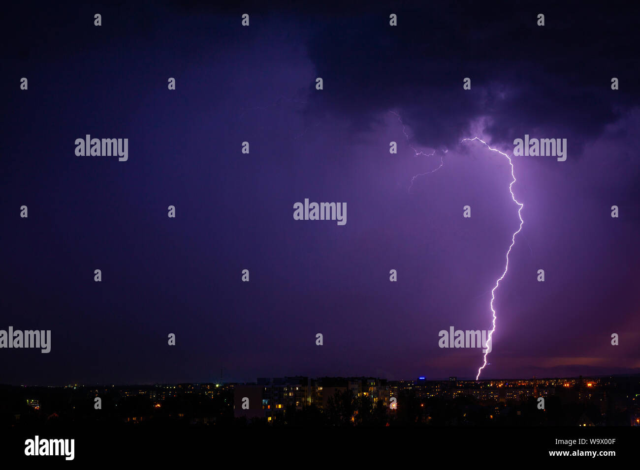 Lightning strikes storm over city purple light Stock Photo - Alamy