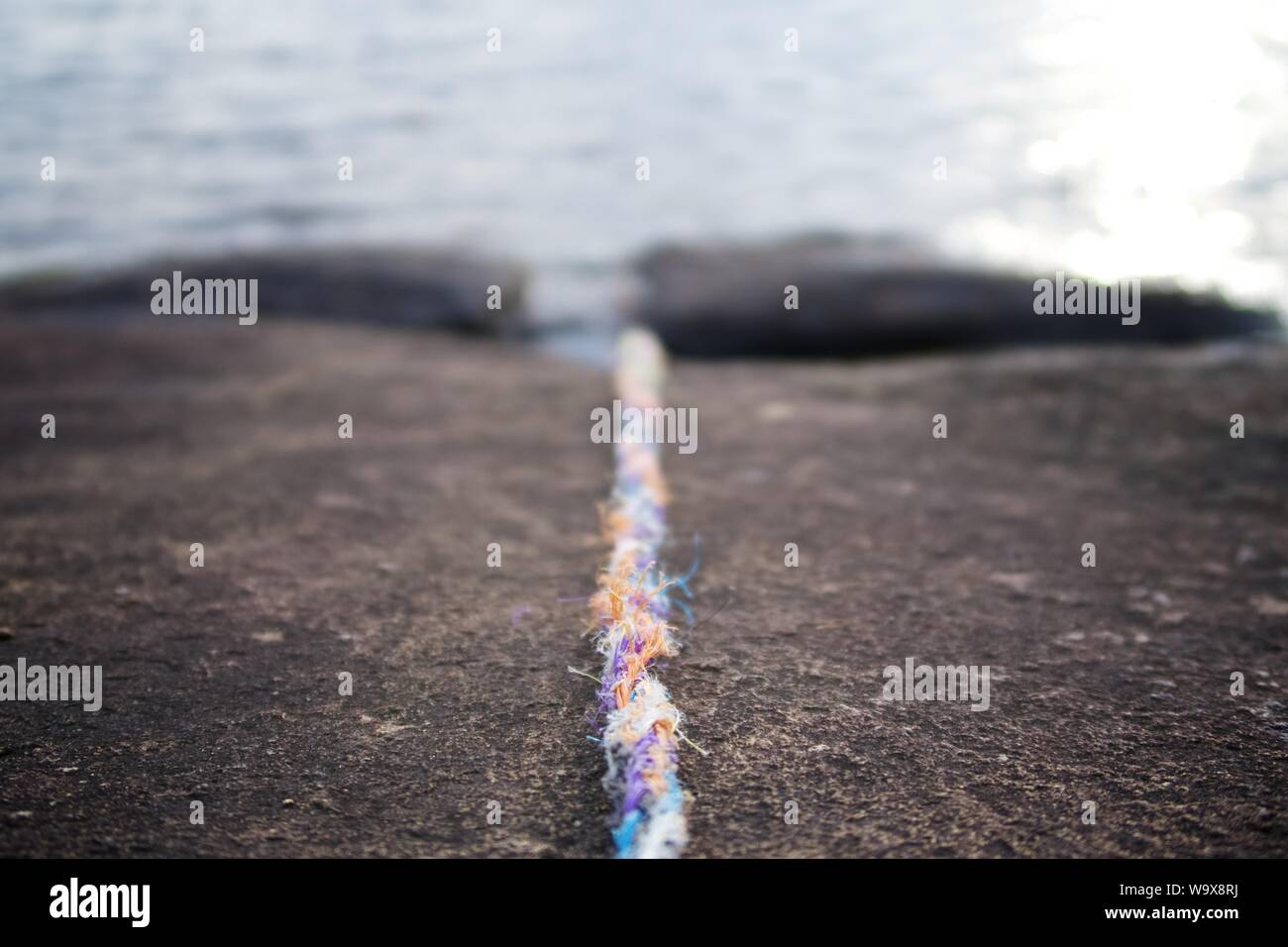 Rope leading into water from a rock, blurred background Stock Photo