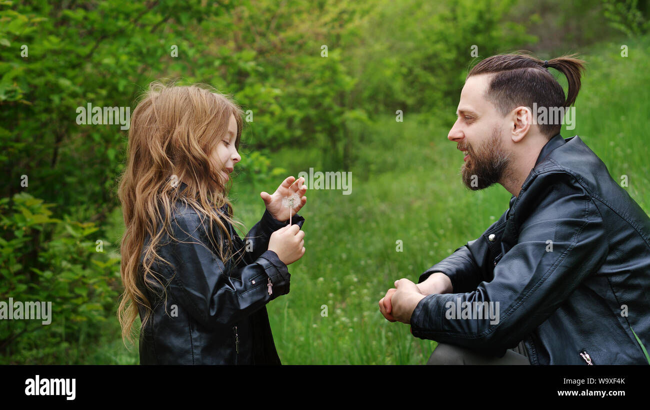 Modern stylish family walking in park. Daughter enjoys chatting with dad. Lovely moments spent to father in nature. Time together. Family look. Urban Stock Photo