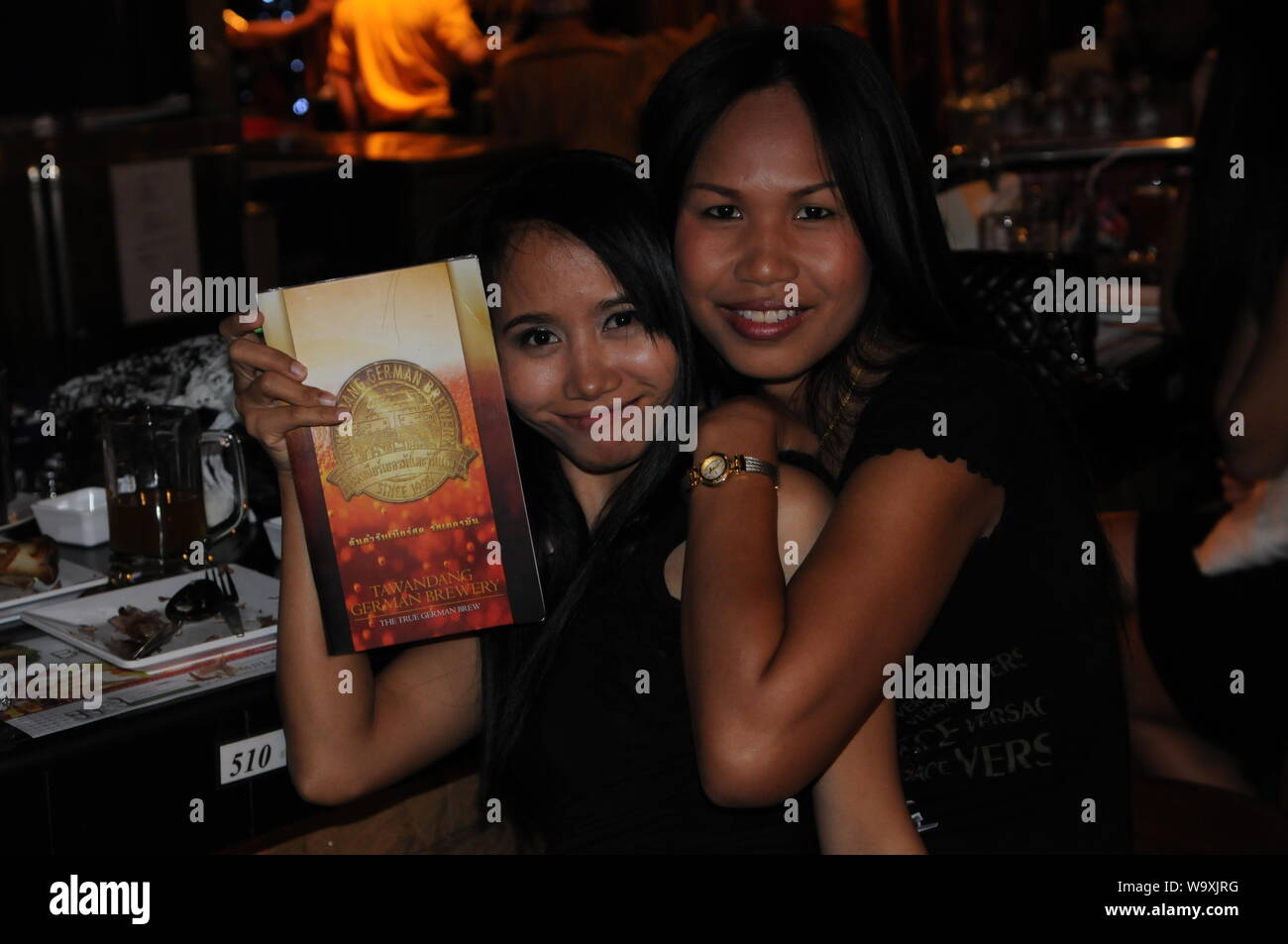 Thai women enjoying New Years Eve & holding a bilingual menu, Tawandang German Brewery, Bangkok, Thailand. credit: Kraig Lieb Stock Photo