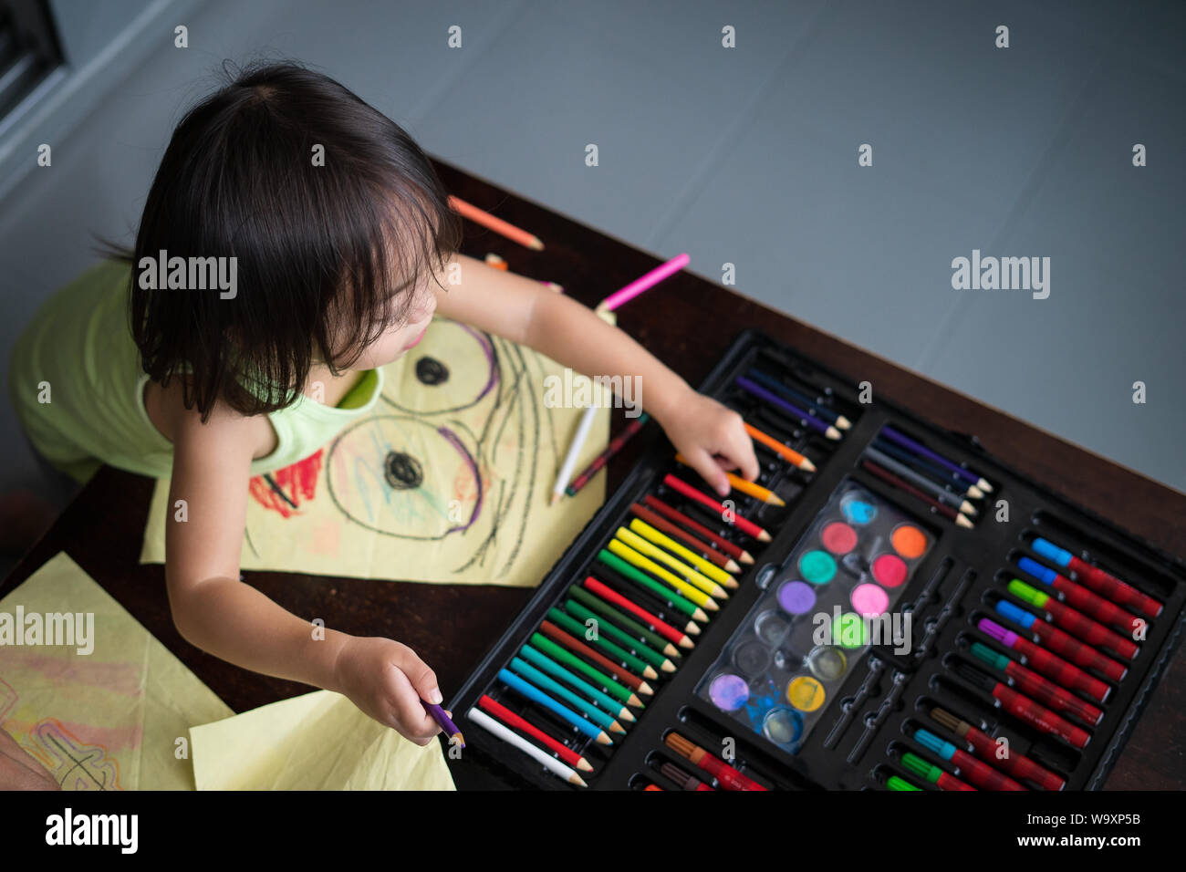 Cute little girl is coloring pages and painting. Children paint. Kids draw. Preschooler with activities at home. Creative toddler Stock Photo