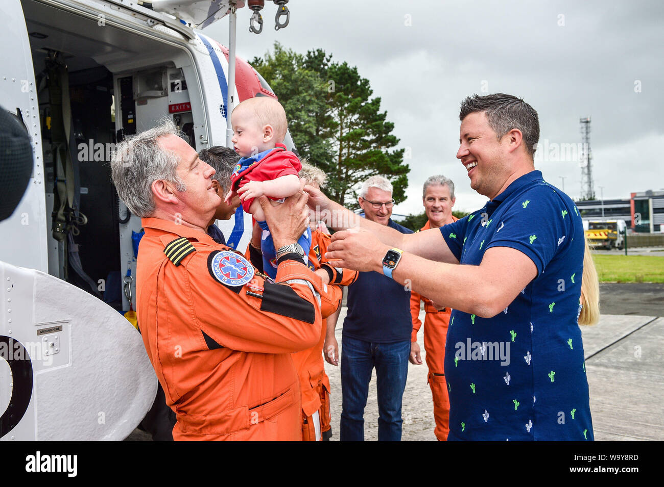 HM Coastguard Chief Crewman Ian Copley lifts one-year-old Jenson Powell from his dad Rich Powell as they meet for the first time in a year since he and his HM Coastguard crew airlifted his wife Jennie (hidden in pic) by helicopter to Oxford from Cornwall after Jennie went into labour at 22 weeks with her twins, giving birth the youngest surviving pre-term twin boys born in Britain. Stock Photo