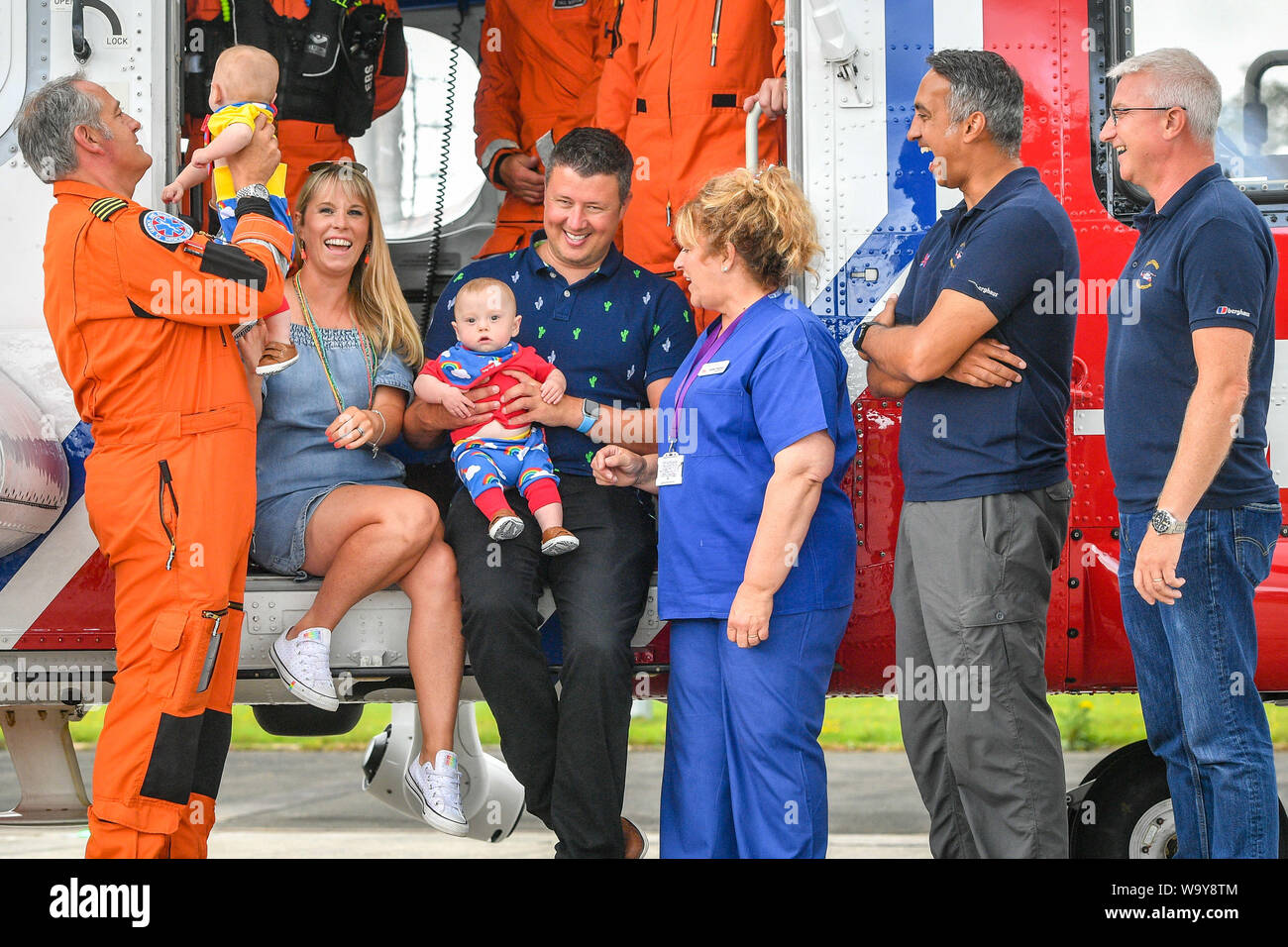Jennie and Rich Powell with their twin boys Jenson, left, Ruben, right, who are celebrating their first birthday by meeting HM Coastguard crews for the first time since Jennie was airlifted by them in a helicopter to Oxford from Cornwall after she went into labour at 22 weeks with her twins, giving birth the youngest surviving pre-term twin boys born in Britain. Pictured (left to right) are Chief Crewman Ian Copley, Jenson, Jennie, Ruben, Rich, Midwife Jane Parke who accompanied Jennie on the flight, Winchman-Paramedic Niall Hanson and Co-Pilot Ivan Hamilton. Stock Photo