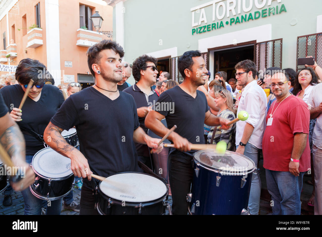 One of music groups entertains the crowd by drumming energetically and marching through the street of Old San Juan for San Sebastian Street Festival. Stock Photo