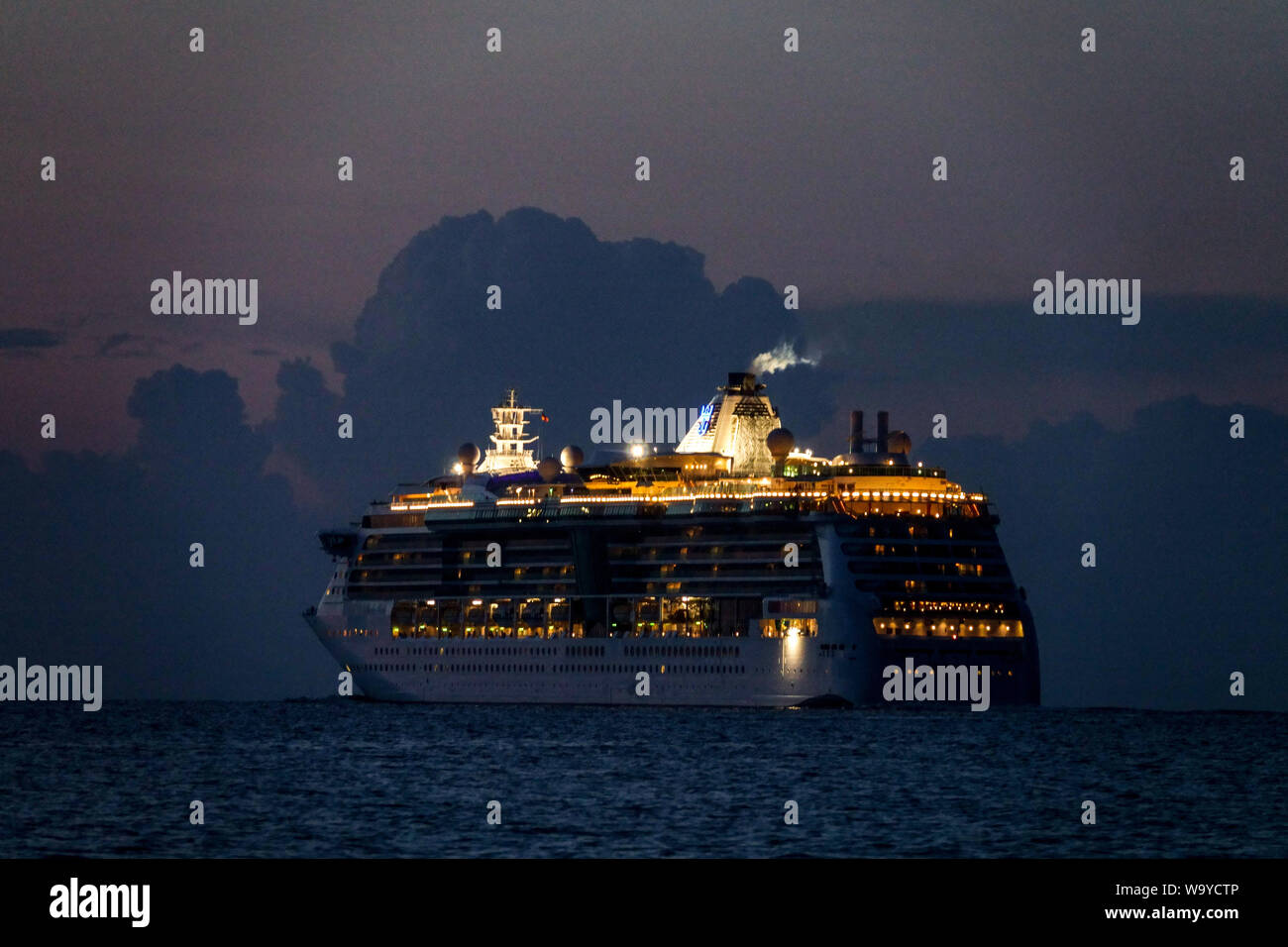 Illuminated cruise ship Serenade of the Seas of the Royal Caribbean International Fleet sailing by Baltic sea, leaving Rostock Germany Stock Photo