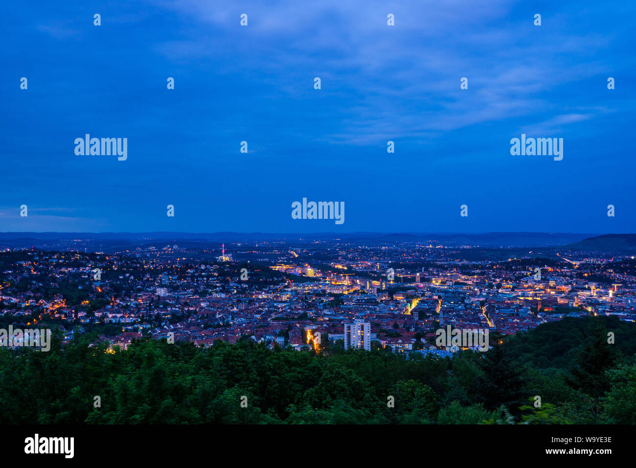 Germany, Houses and streets of stuttgart city glowing in evening dawning mood in the middle of green nature landscape from above monte scherbelino Stock Photo