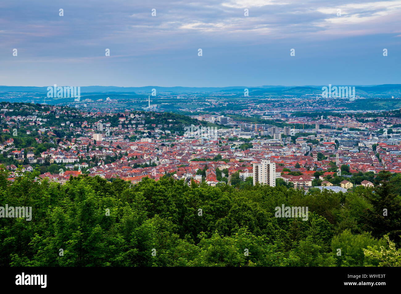 Germany, Houses of city stuttgart in valley surrounded by many hills and mountains forested with green trees in beautiful nature landscape Stock Photo