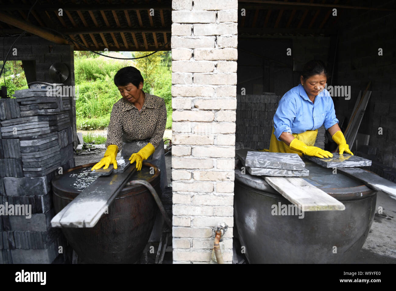 (190816) -- JINGXIAN, Aug. 16, 2019 (Xinhua) -- Workers polish bricks at a brick making factory in Maolin town of Jingxian county, east China's Anhui Province, Aug. 15, 2019. The brick with natural patterns, peculiar to the town of Maolin, is a kind of decorative material for ancient building, mainly used on door, wall and window. Fired with two different mud, the brick shows two different colors with delicate texture. During the Ming (1368-1644) and Qing (1644-1911) dynasties, such brick was widely used on local residential architectures. However, the brick making techniques were once almo Stock Photo