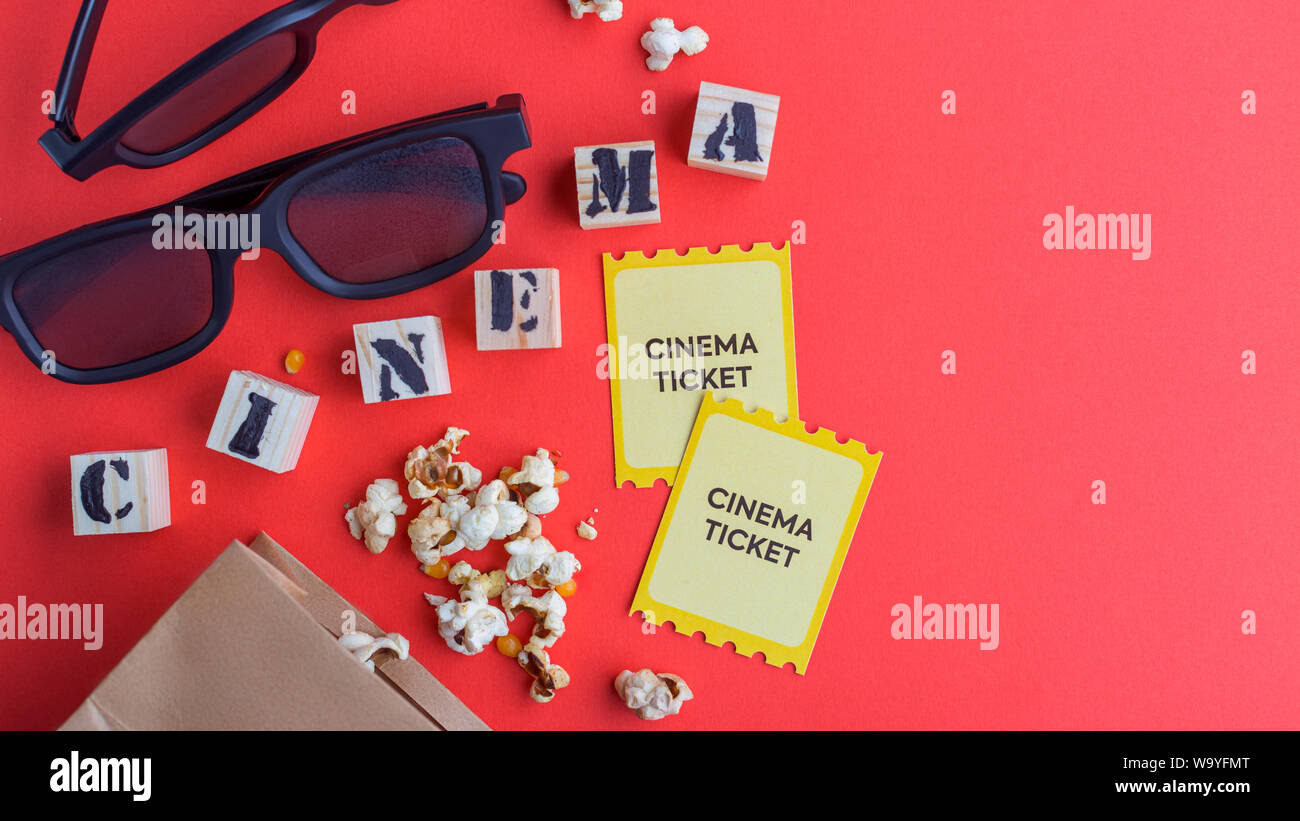 craft bag with popcorn 3d cinema glasses tickets wooden cubes with text on red background creative flatlay Stock Photo