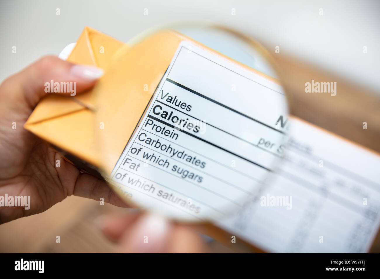A Person Looking Nutrition Facts On Package Through Magnifying Glass Stock Photo