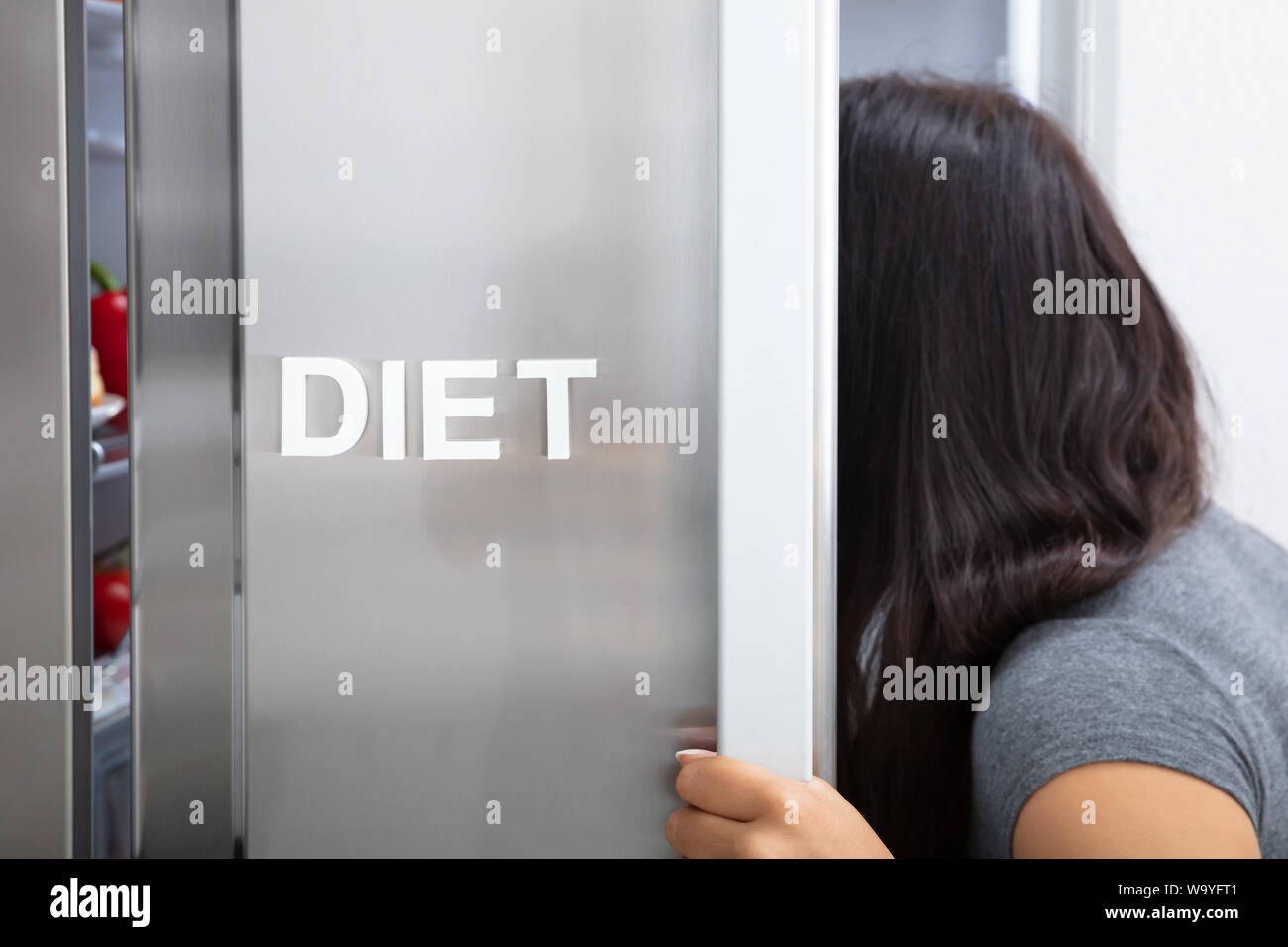 Close-up Of Woman Searching Diet Food In Opened Refrigerator Stock Photo