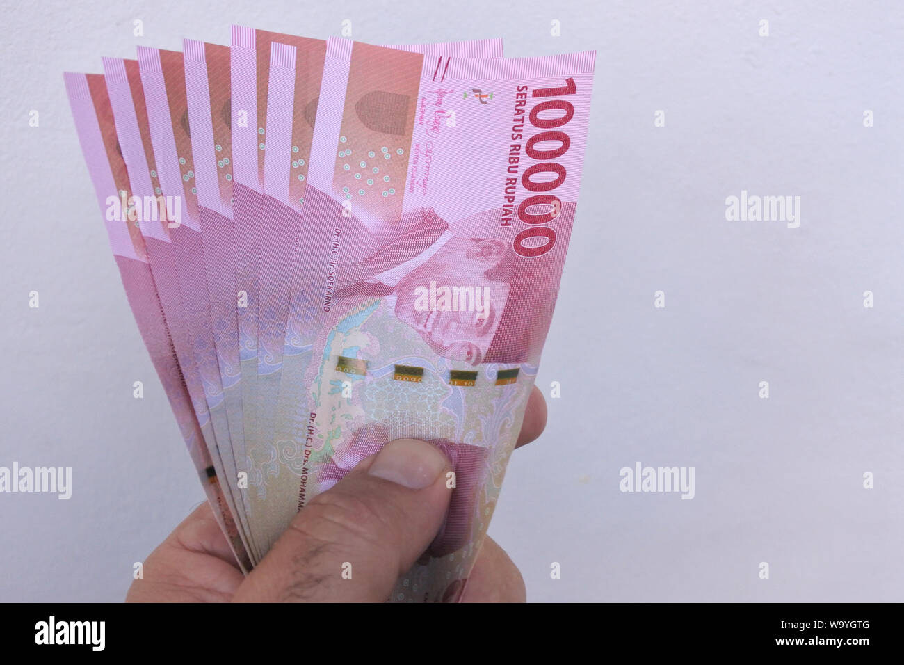 man holding 100000 indonesian rupiah currency of indonesia bank notes W9YGTG