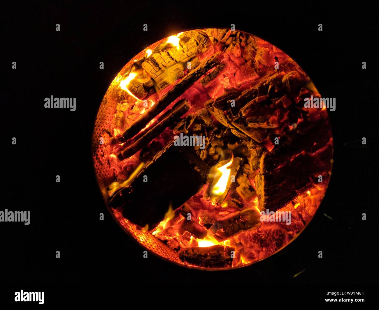 Closeup shot of firewood burning in a round stove Stock Photo
