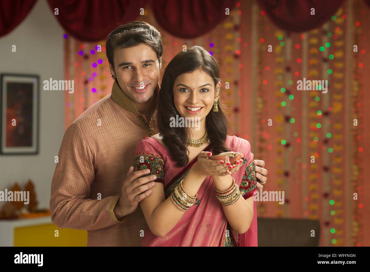 Young couple holding a Diya and smiling Stock Photo